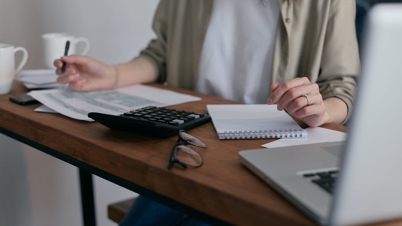 Person sitting at a desk with calculator, paper, and computer