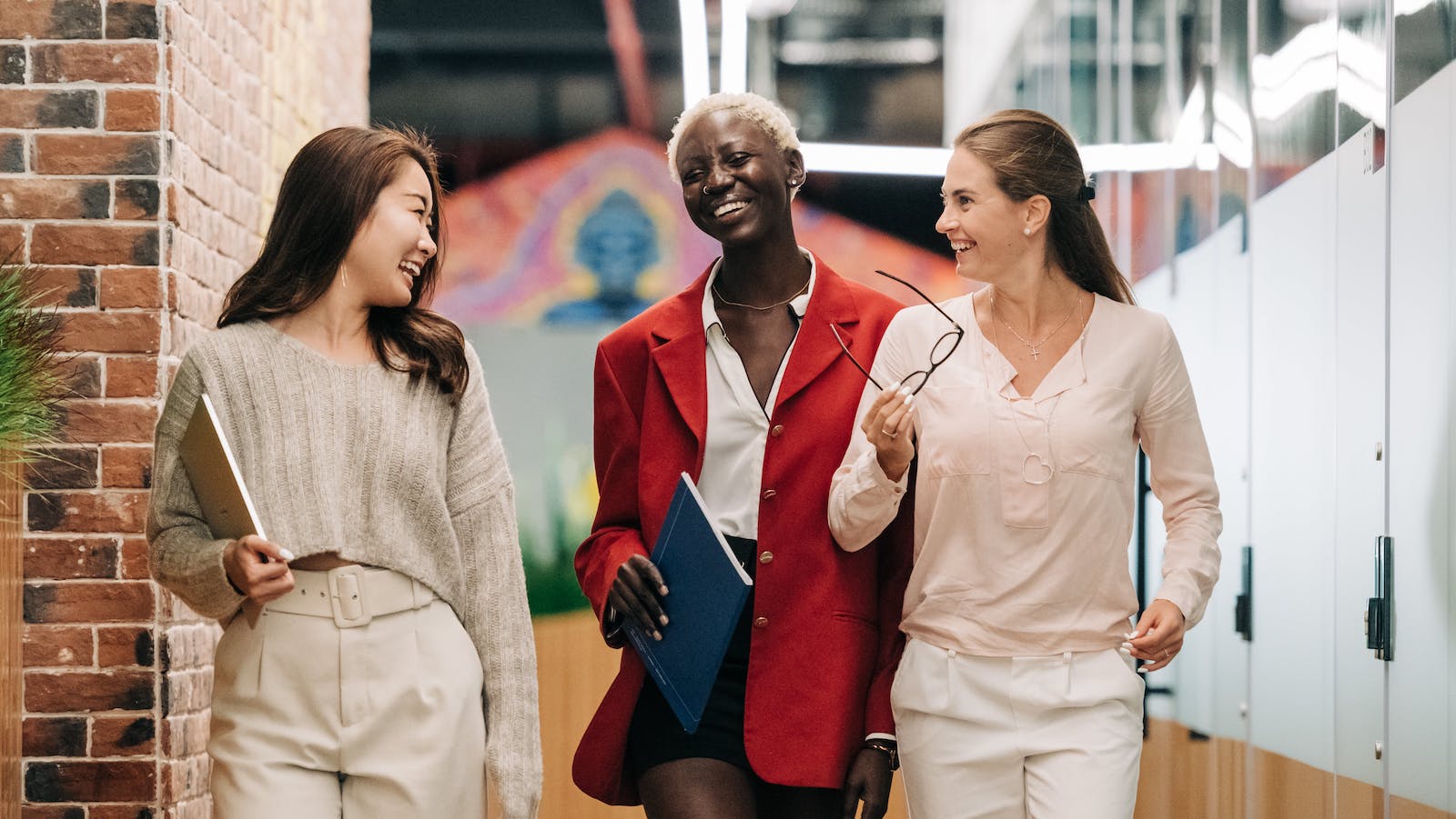 businesswomen smiling and walking together in modern workplace