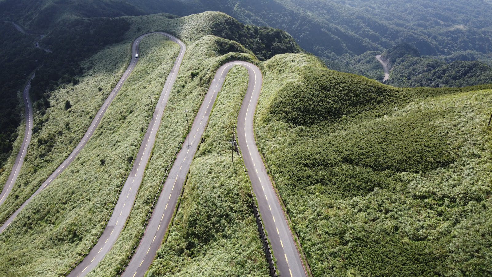 A Car Driving on a Winding Asphalt Road on a Mountain