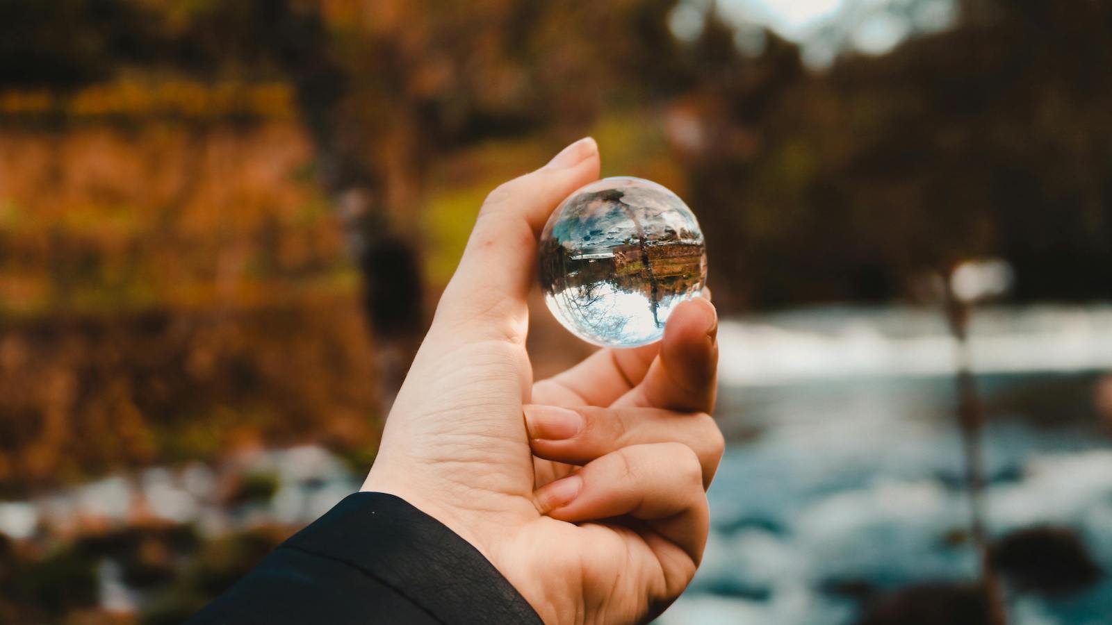 Person holding a clear sphere in nature