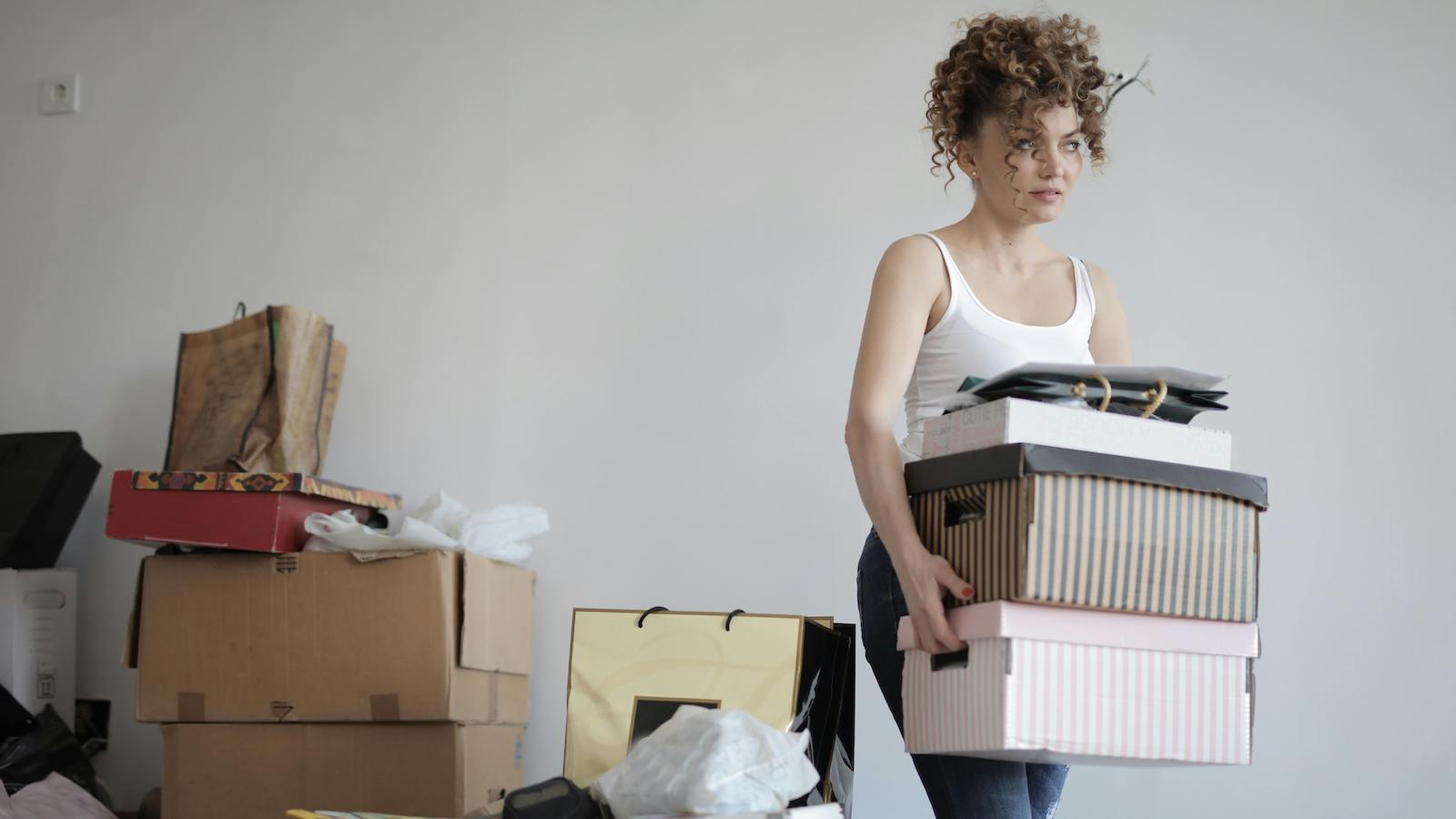 Concentrated woman carrying stack of cardboard boxes for relocation