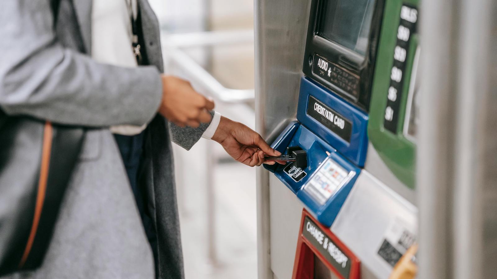 Woman inserting credit card into subway ticket machine