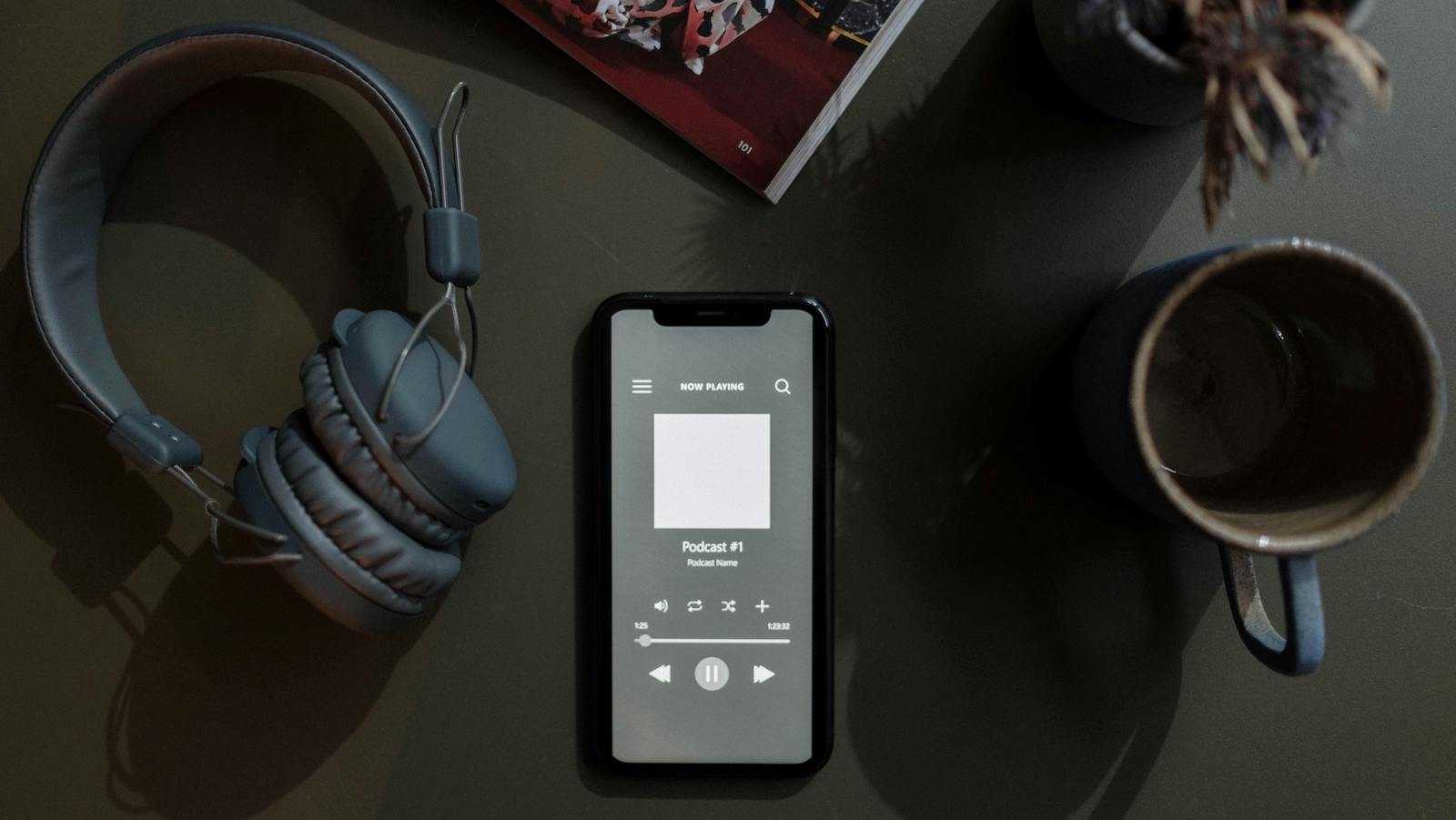 Overhead Shot of a Cellphone between a Mug and Headphones