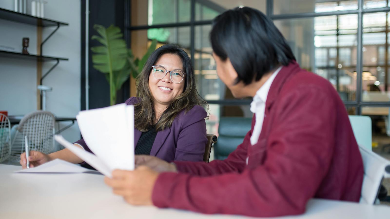 Woman in Purple Blazer Smiling while Holding a Pen