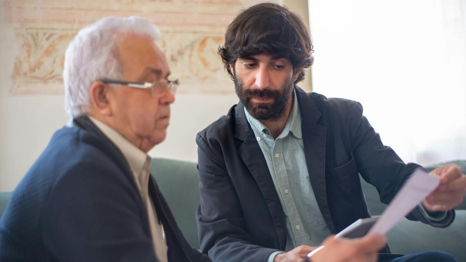 Bearded Man Showing an Elderly Client a Document
