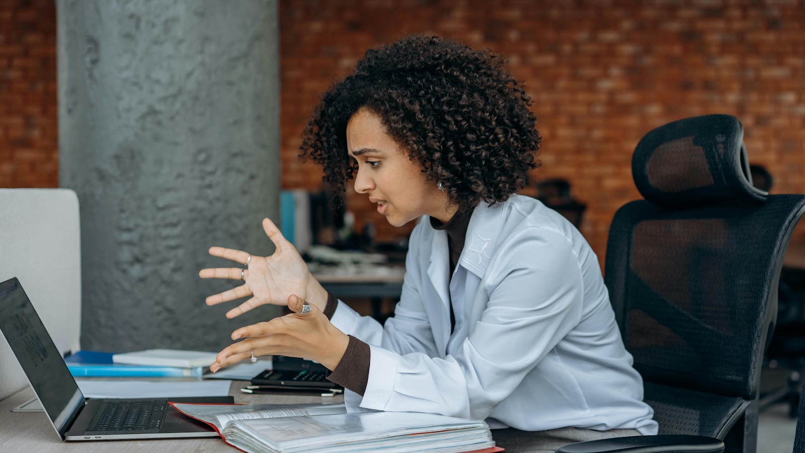 A Frustrated Woman Sitting on a Swivel Chair while Looking at the Screen of a Laptop