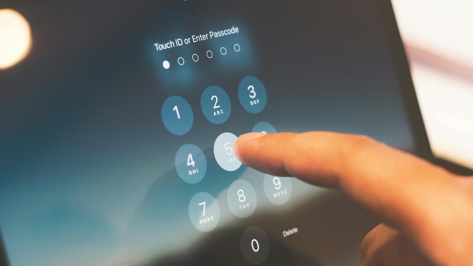 Index finger on a screen typing in a six digit passcode starting with 5
