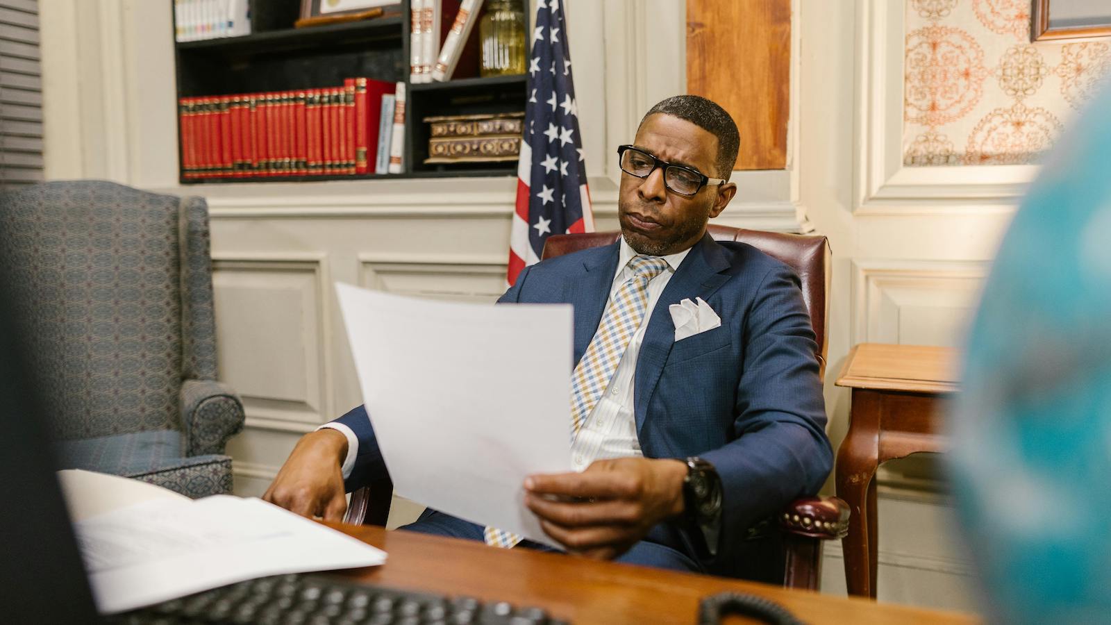 An Attorney in Blue Suit Holding a Document while Sitting