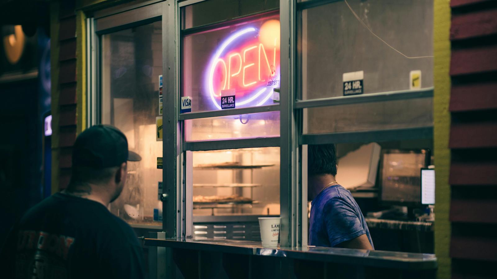 A Man Standing in Front of the Food Stall with Open Sign