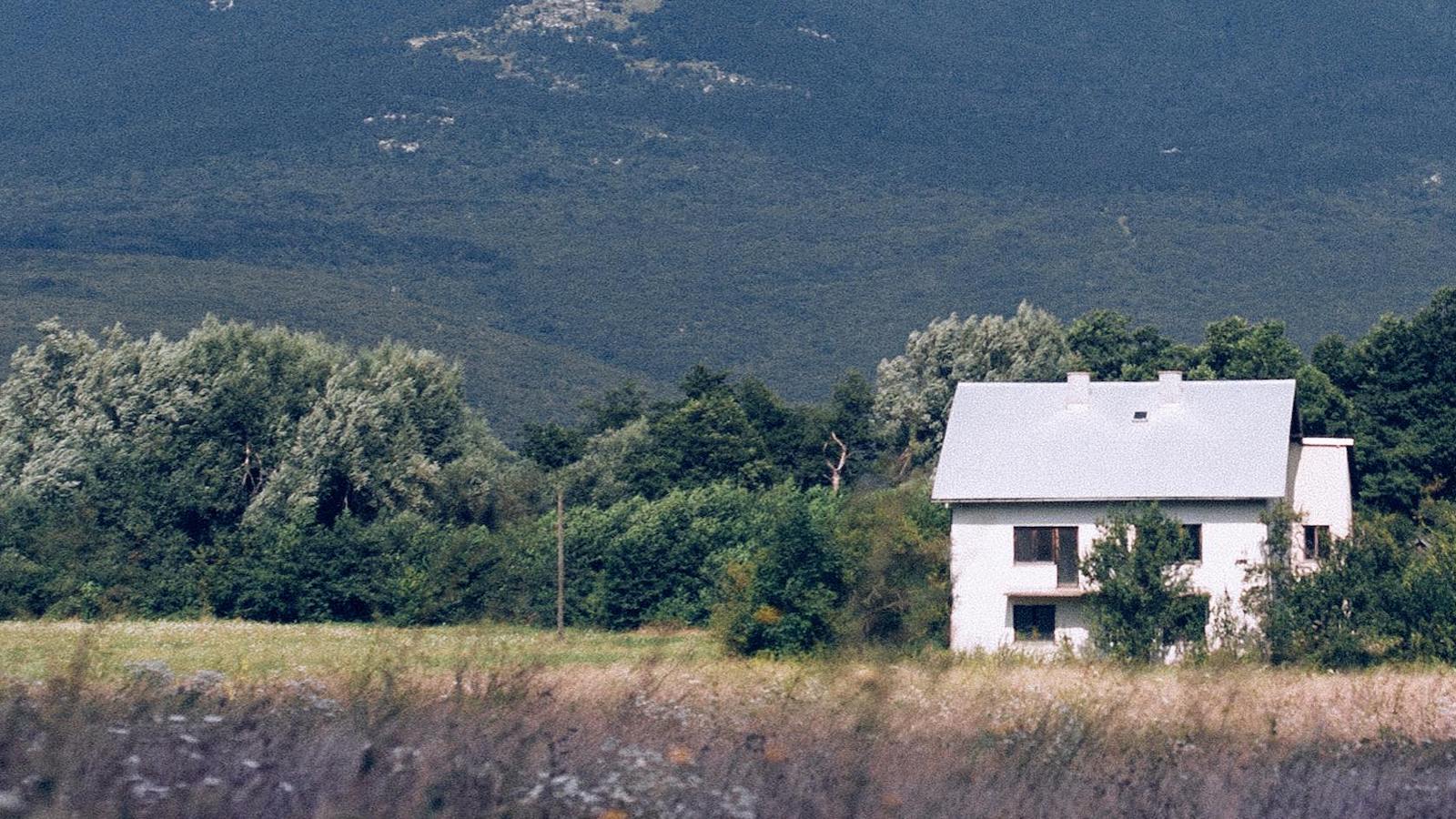 Small house located near grassy field and mountains