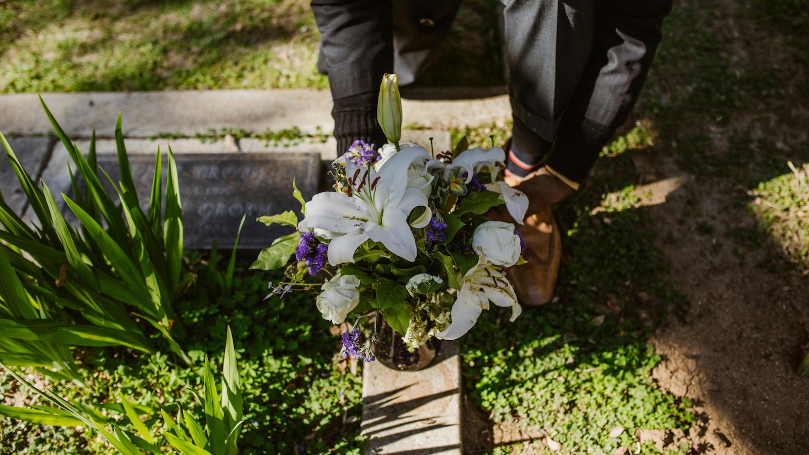 Man Placing a Bunch of Flowers on a Grave