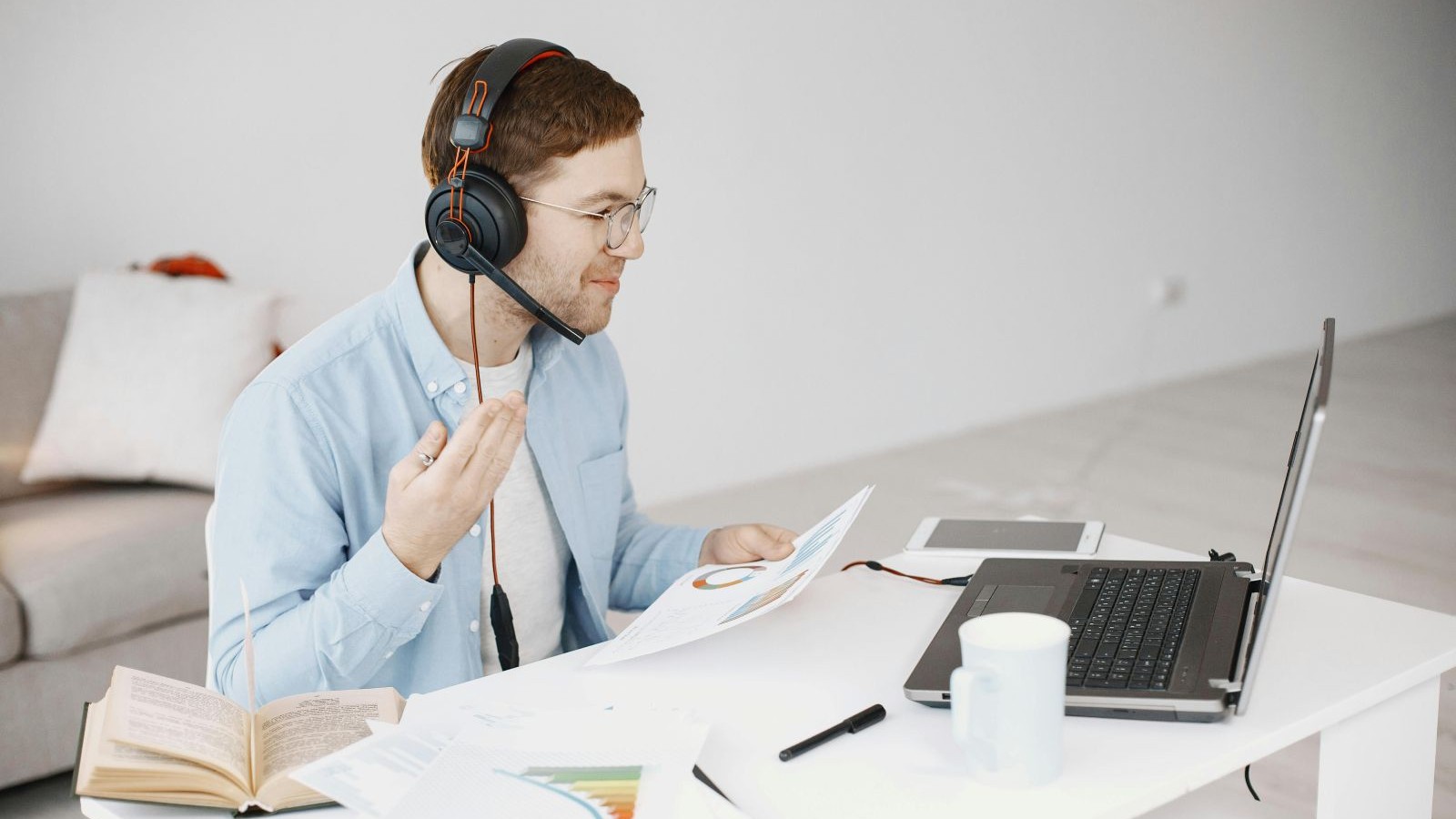 Man sitting at a desk with a headset on and papers and a computer in front of him