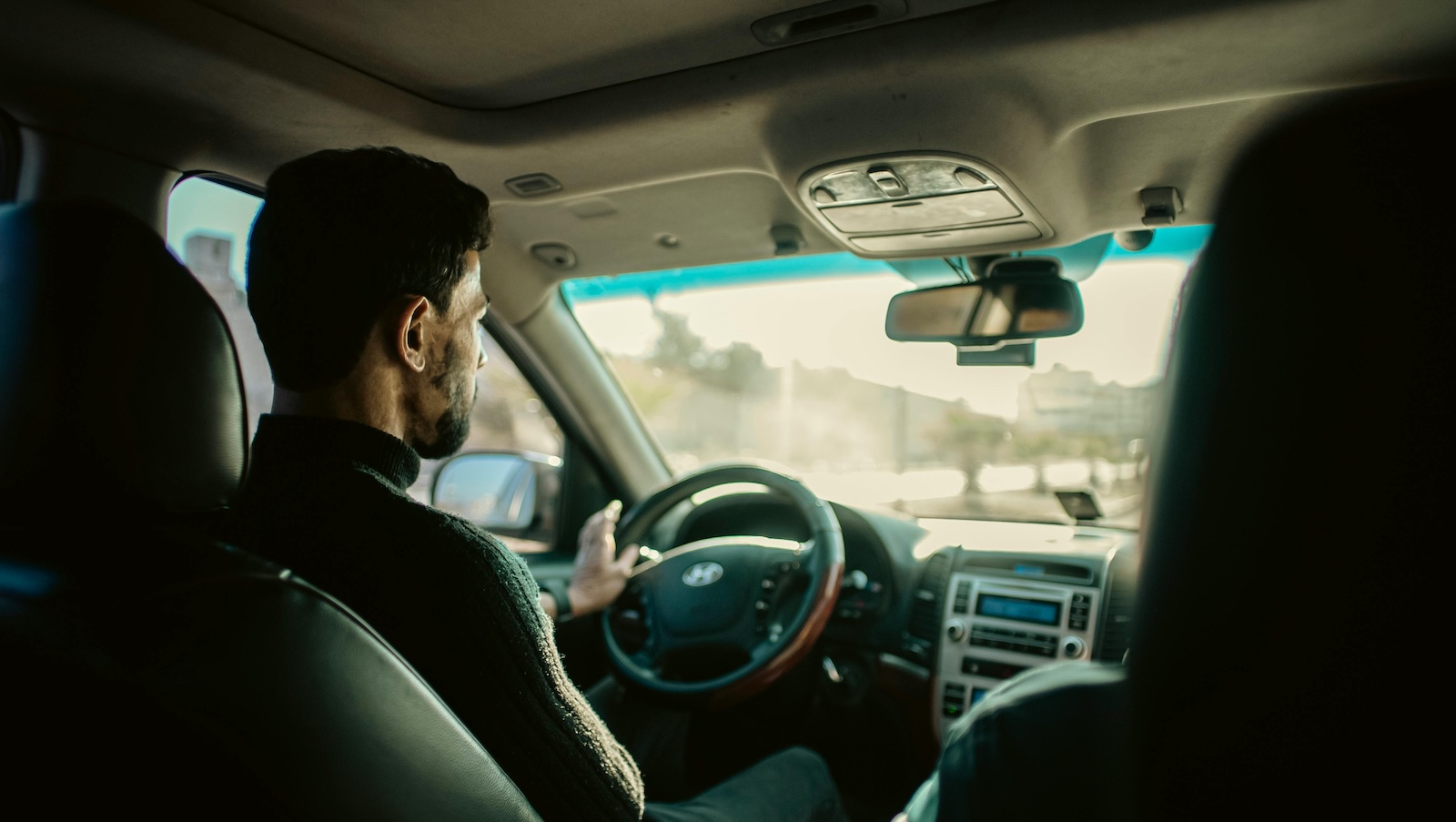 Backseat view of a man driving a car during the daytime