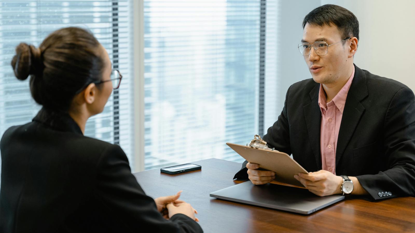 Two professionals discussing at an office table, indicating a formal meeting setting.