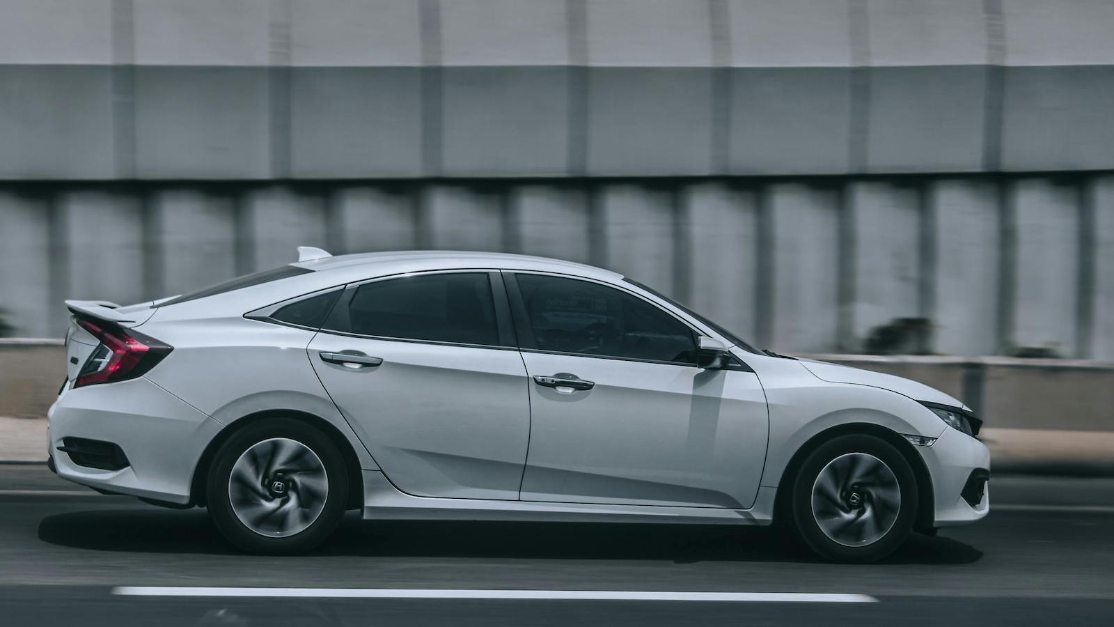 A sleek white car speeding down an urban road.