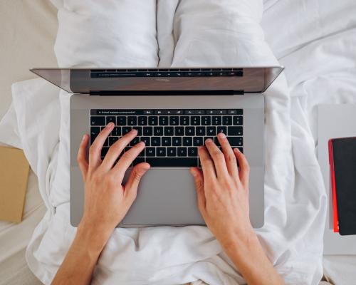 Person in bed typing on a laptop