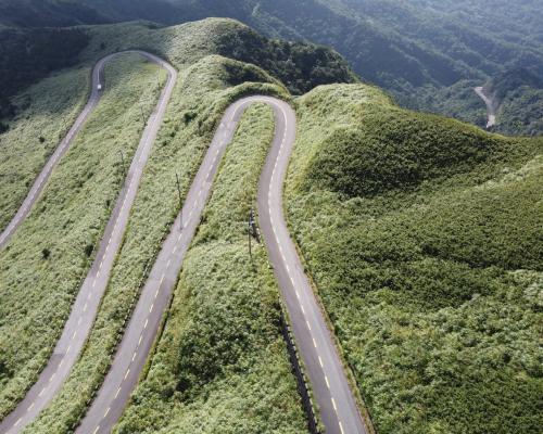A Car Driving on a Winding Asphalt Road on a Mountain