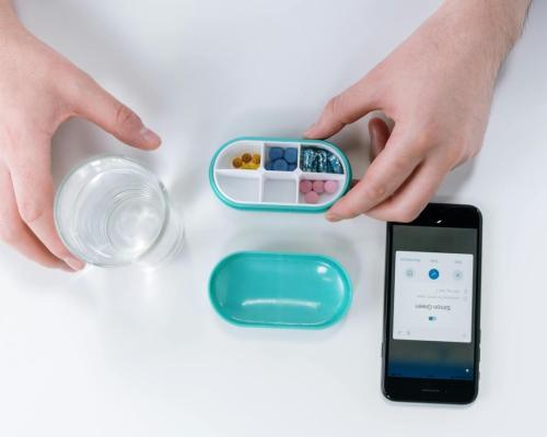 Person Holding Pill Box with Glass of Water and Phone