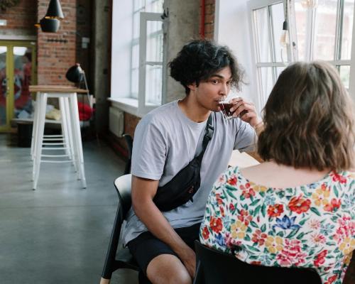 Two young people sitting in a cafe with windows drinking espresso