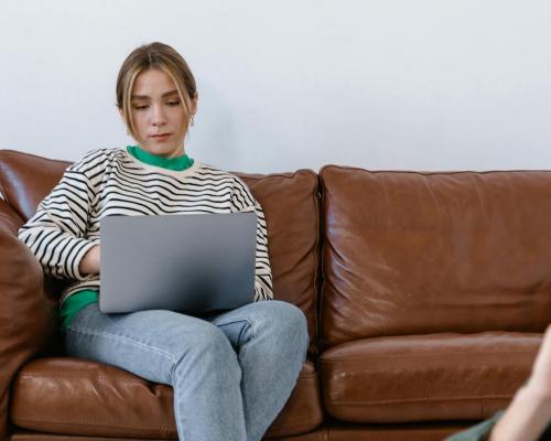 A Woman in a Black and White Stripe Shirt and Blue Denim Jeans Sitting on Brown Sofa