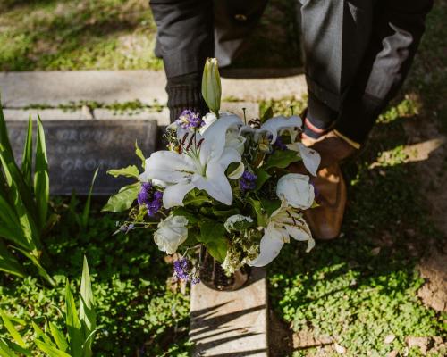 Man Placing a Bunch of Flowers on a Grave