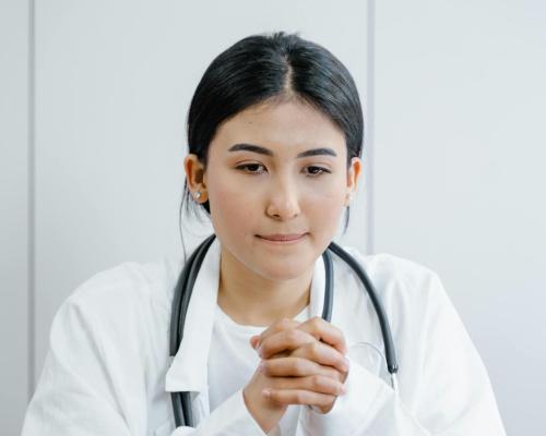 Woman in White Scrub Suit Wearing Black and Gray Stethoscope
