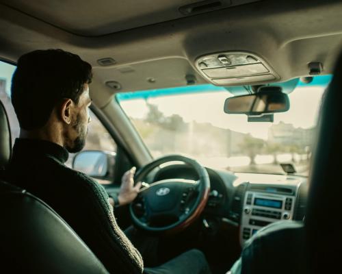 Backseat view of a man driving a car during the daytime