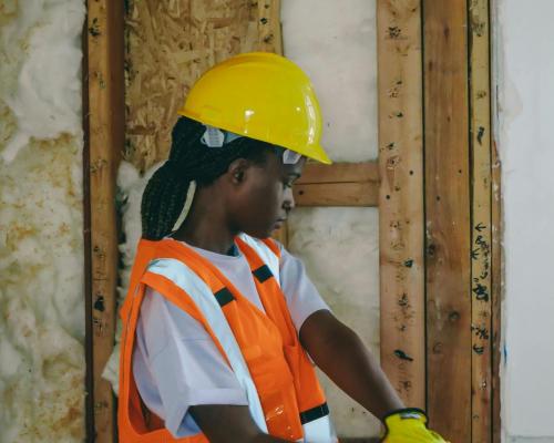 Construction worker in PPE hammering indoors on a renovation site.