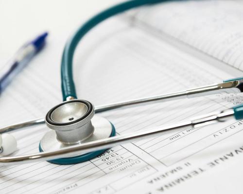 A stethoscope and pen resting on a medical report in a healthcare setting.