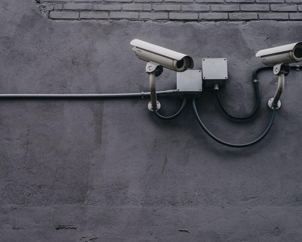 Two security cameras at the top right of a dark grey wall