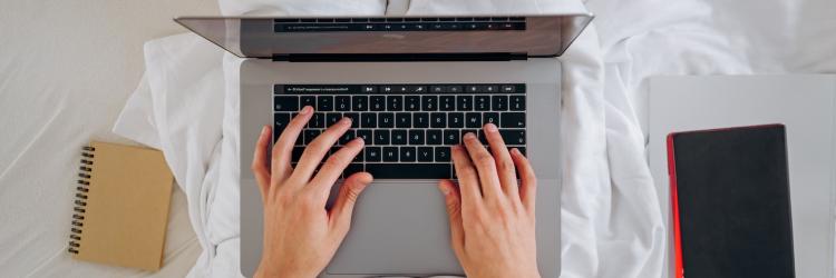 Person in bed typing on a laptop
