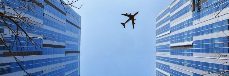 A plane flying above two tall buildings