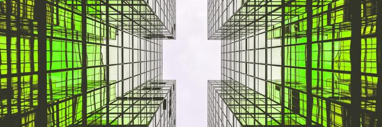 Low angle photo of two tall buildings with green lights