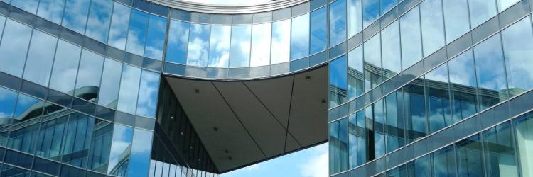 A glass office building against a blue sky