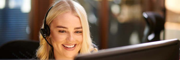 Woman looking at computer talking on a head set