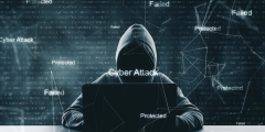 a hoodie by a computer with binary script behind it and the words cyber attack