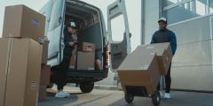 Two people unloading boxes from van