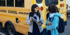 Two young students in front of a school bus