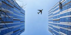 A plane flying above two tall buildings