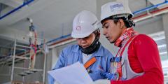 Two people in hard hats looking at a sheet of paper