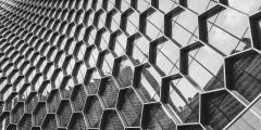 Greyscale architectural photo of a glass building with hexagons
