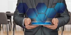 A person holding a tablet with holographic blue hexagons coming out of it