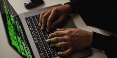 Close-up image of a person typing on a keyboard with bright green words on a black screen