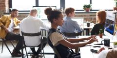 Woman in White and Black Top Using Computer in a room with other people on their laptops