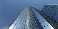 Low-angle view of a very tall glass/mirrored building against a pure blue sky