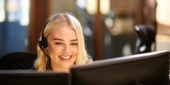 Woman looking at computer talking on a head set