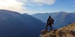 Person with backpack standing on a mountain facing away